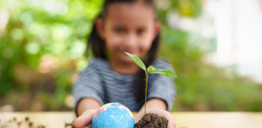 Blurred of little girl is holding plant and globe model together